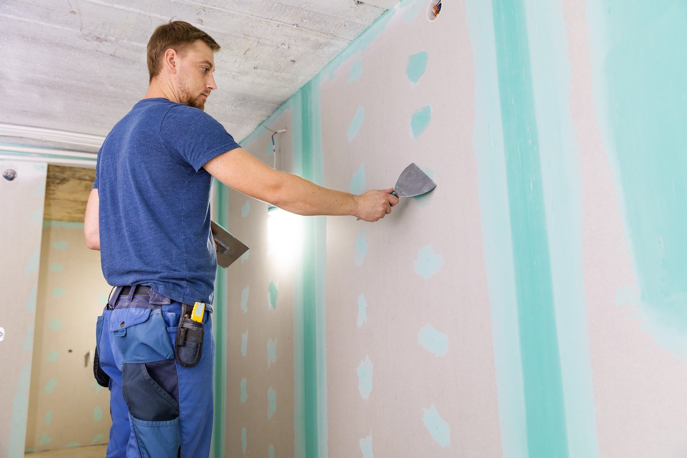 apartment interior construction - worker plastering gypsum board wall